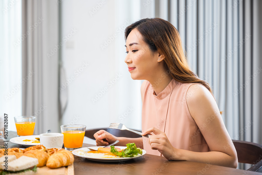 Woman eat fresh breakfast served food with beverage before go to work in the morning at home, Asian young female sitting kitchen table food having eating healthy breakfast at home