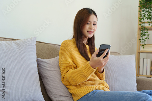 woman sitting on sofa at home ready to use mobile phone