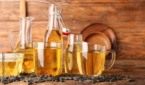 Glassware of sunflower oil and seeds on wooden background