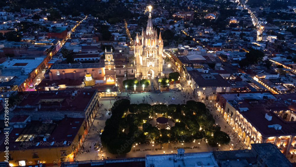 the church Parroquia Archangel Jardin Town Square Night Tree Decoraciones San Miguel de Allende, México. Parroaquia. Night and morning light in a drone view.