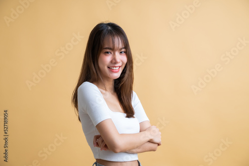 Young attractive Asian woman with arms crossed isolated on yellow background