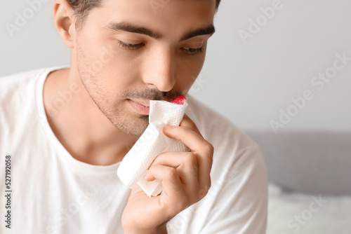 Young man wiping nosebleed ...