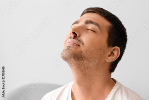Young man with nosebleed at home, closeup