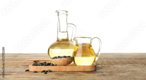 Board with sunflower oil and seeds on wooden table against white background
