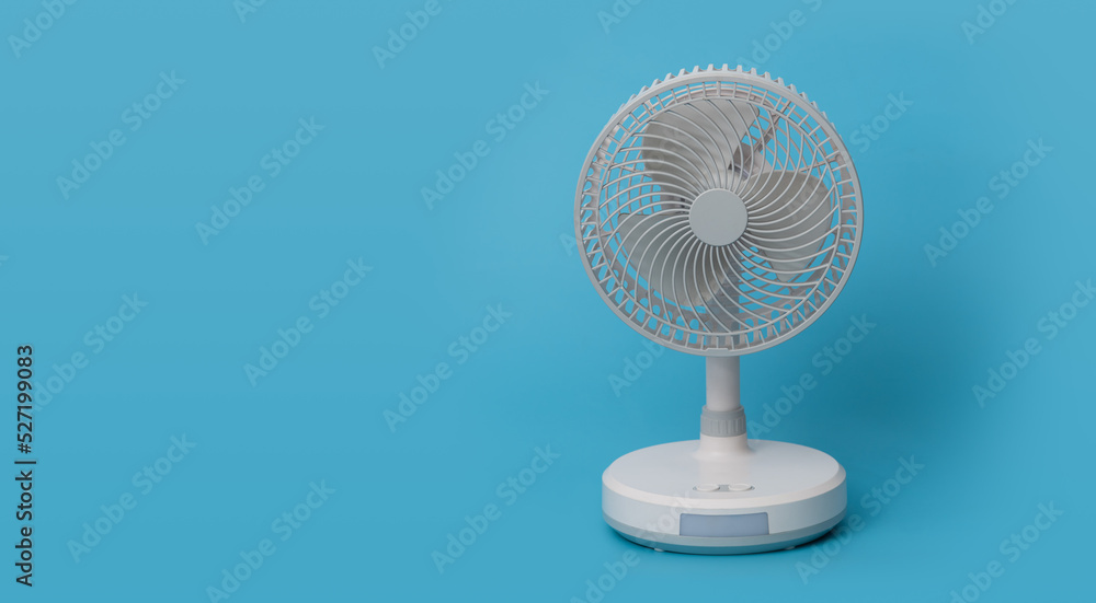 White desktop electric fan on blue background.