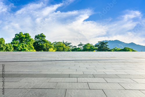 Empty square floor and green forest with mountain scenery under blue sky