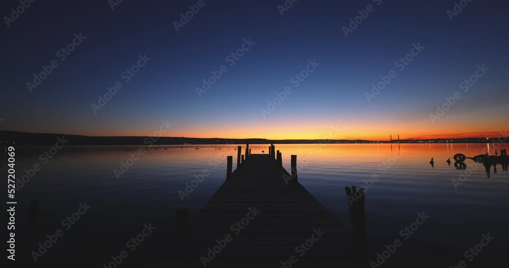 Small Dock and Boat at the lake and colorful sunset over the water. Lonely fishing jetty nature landscape. Small Dock and Boat at the lake and colorful sunset over the water. Lonely fishing jetty nature landscape.