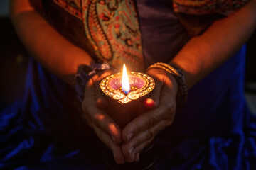 Diwali Festival of lights celebration. Diya lamp in woman hands, close up