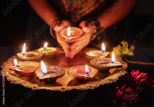 Diwali Festival of lights celebration. Diya lamp in woman hands, close up photo