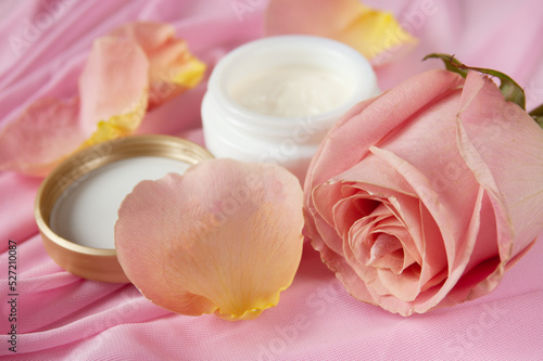 Cream cosmetic in bottle  fresh pink rose flowers and pink silk  natural cosmetic