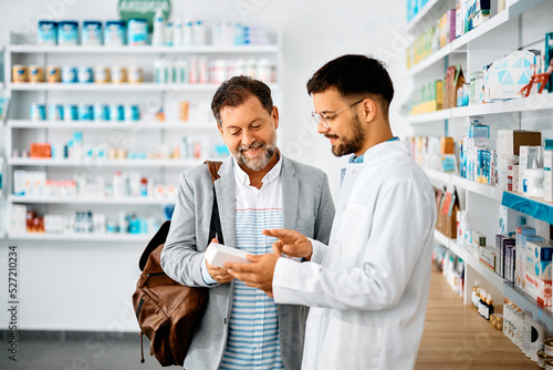 Happy man chooses medicine with help of young pharmacist in drugstore. photo