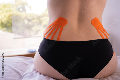 Close-up of a female back with kinesio taping, kinesio tape on back of the patient photo