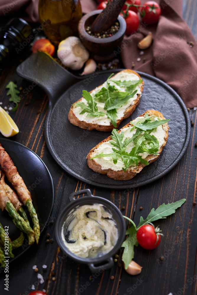 Tasty breakfast - toasts with cream cheese and Asparagus wrapped with bacon and spices on a plate