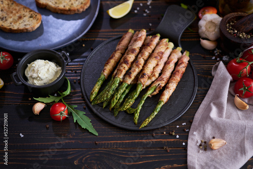 Healthy food - Asparagus wrapped with bacon and spices on a plate on wooden table
