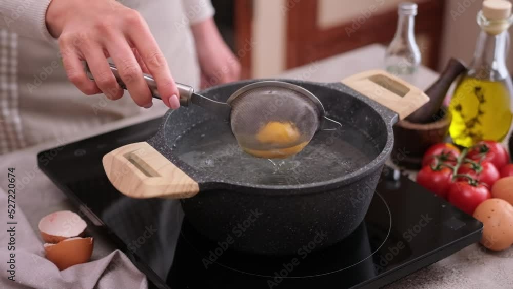 Poached egg - woman puts into a pot of hot boiling water Poached egg - woman puts into a pot of hot boiling water