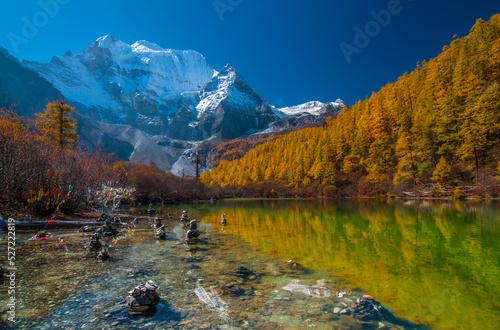 Autumn scenery Pearl Lake, The holy peak Xiannairi Peak (Chenresiq) can been seen in the background. in Yading national reserve, Daocheng, Sichuan Province, China. photo