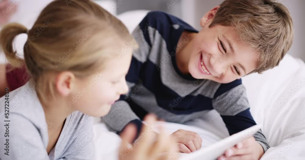 Children with a tablet for online game or digital learning education together on the bed while on holiday or vacation. Happy boy, girl or young people looking at funny meme content on a kid website Children with a tablet for online game or digital learning education together on the bed while on holiday or vacation. Happy boy, girl or young people looking at funny meme content on a kid website