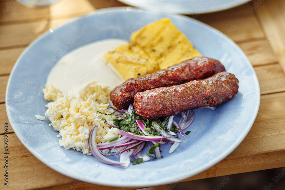 Romanian cuisine, traditional sausage called mici or mititei served with brynza, red onion and mamaliga Romanian cuisine, traditional sausage called mici or mititei served with brynza, red onion and mamaliga
