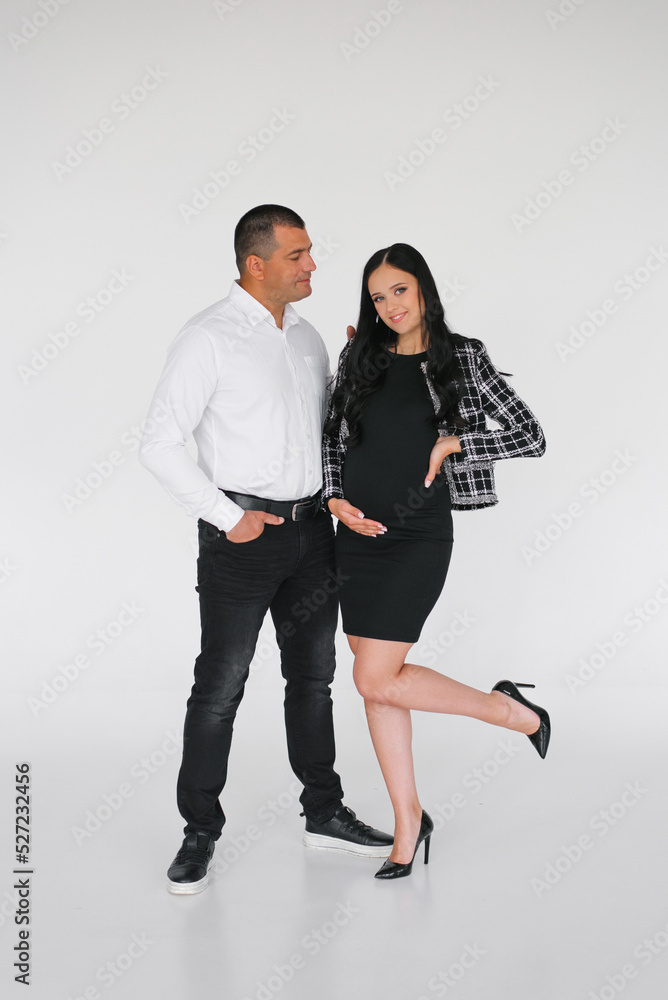 Stylish young family is expecting a baby. Pregnant wife with her husband on a light background Stylish young family is expecting a baby. Pregnant wife with her husband on a light background