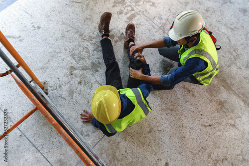 First aid support accident at work of construction worker at site. Builder accident falls from the scaffolding on floor, Safety team helps employee accident.