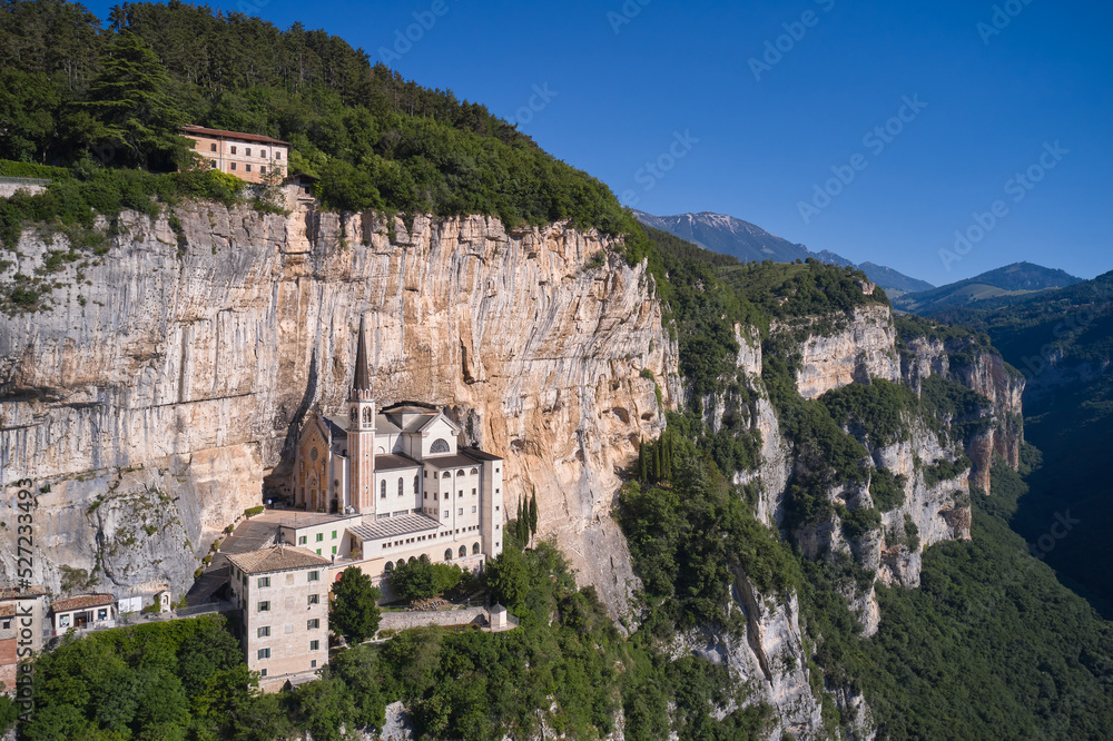 Fototapeta premium Church in the rock, Santuario della Madonna della Corona. Madonna della Corona Sanctuary view, surrounded by mountains. An old church, built around 1625, on a quiet, picturesque mountainside.