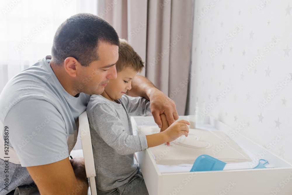 Obraz premium Dad and his baby son play at home with quartz sand