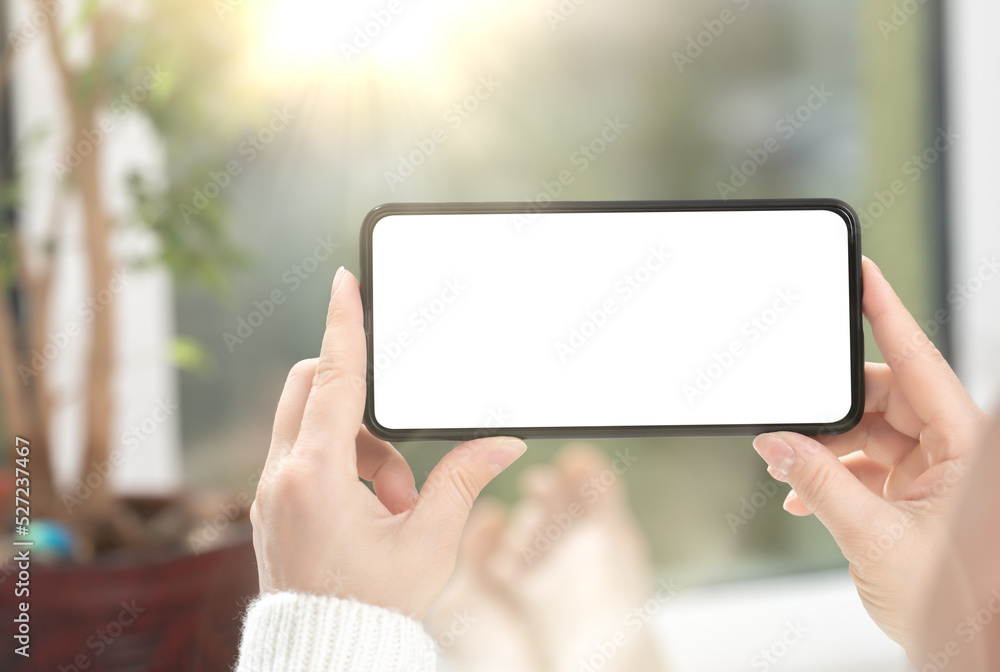 Woman watches video content or playing game on cell phone or mobile smartphone with white blank screen. mockup cellphone at home Woman watches video content or playing game on cell phone or mobile smartphone with white blank screen. mockup cellphone at home
