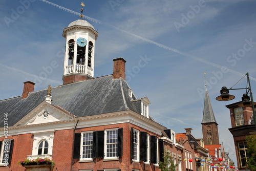 The Oud Stadhuis (Old town hall, built in 1610) of Dokkum, Friesland, Netherlands, with the bell tower of Martinus and Bonifatius church in the background photo