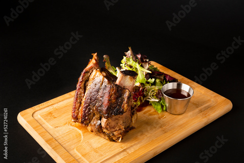 Big piece of beef rib on a wooden table over a black background
