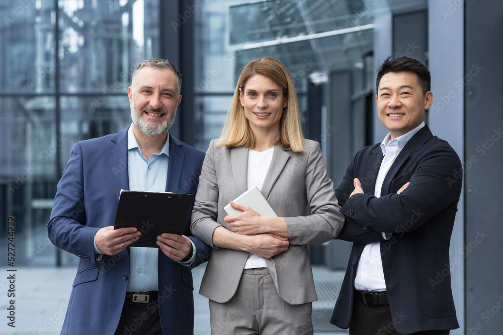 Successful dream team, diverse business group of asian man and business woman smiling and looking at camera, colleagues with crossed arms outside office building, professionals investors and bankers