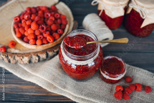 Jar with a spoon and raspberry jam with craft decor
