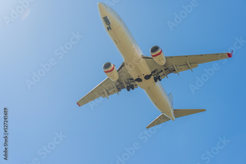 Looking up at the under carriage of a large jet as it flies overhead in a blue sky photo