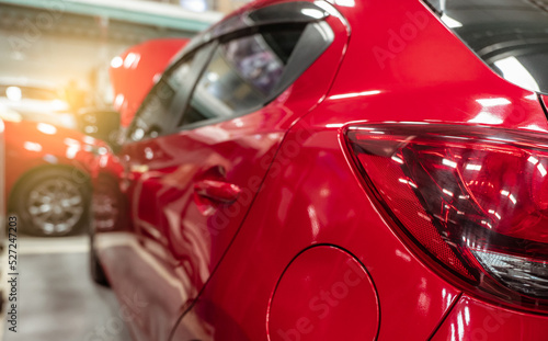 Rear view of red SUV car parked in car repair shop. Red car in workshop of service station. Vehicle inside garage workshop. Cleseup tailight. Red car in garage for repair and maintenance service.