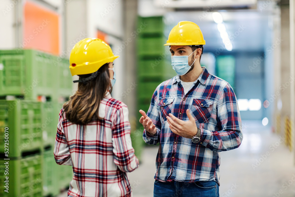 Two factory workers talking about business in warehouse during covid 19. Two factory workers talking about business in warehouse during covid 19.