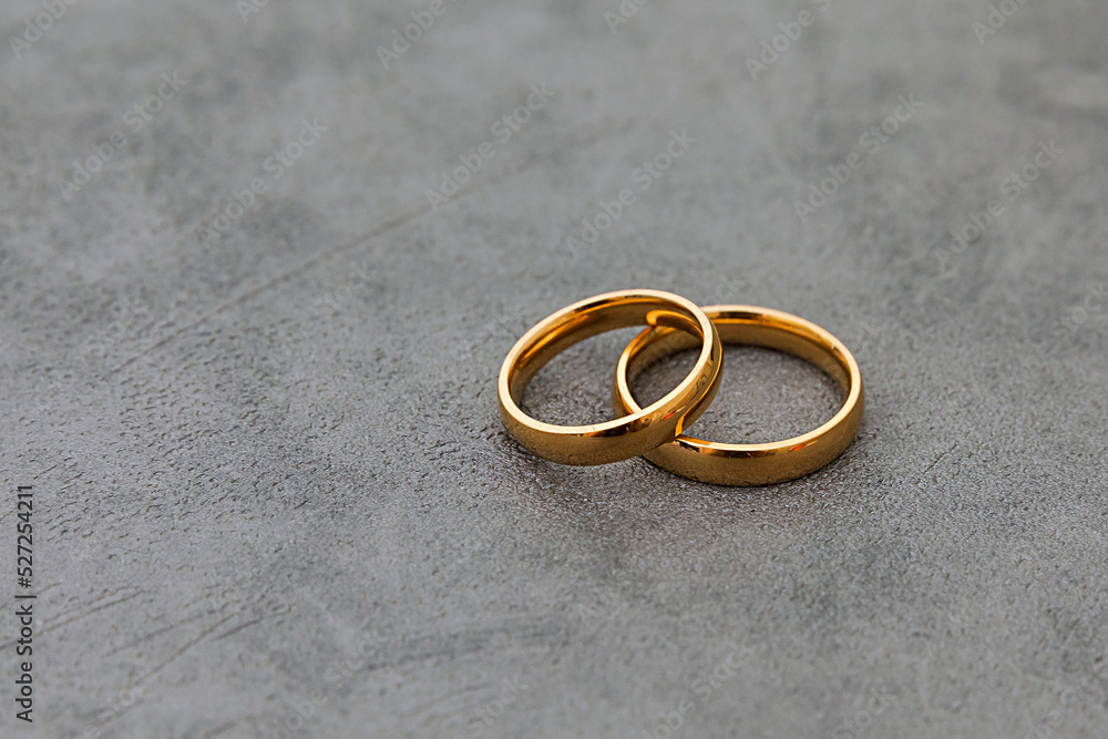 Will you marry me. Two golden wedding rings on concrete stone grey background. Engagement marriage proposal wedding concept. Banner on wedding day with copy space. Wedding day details