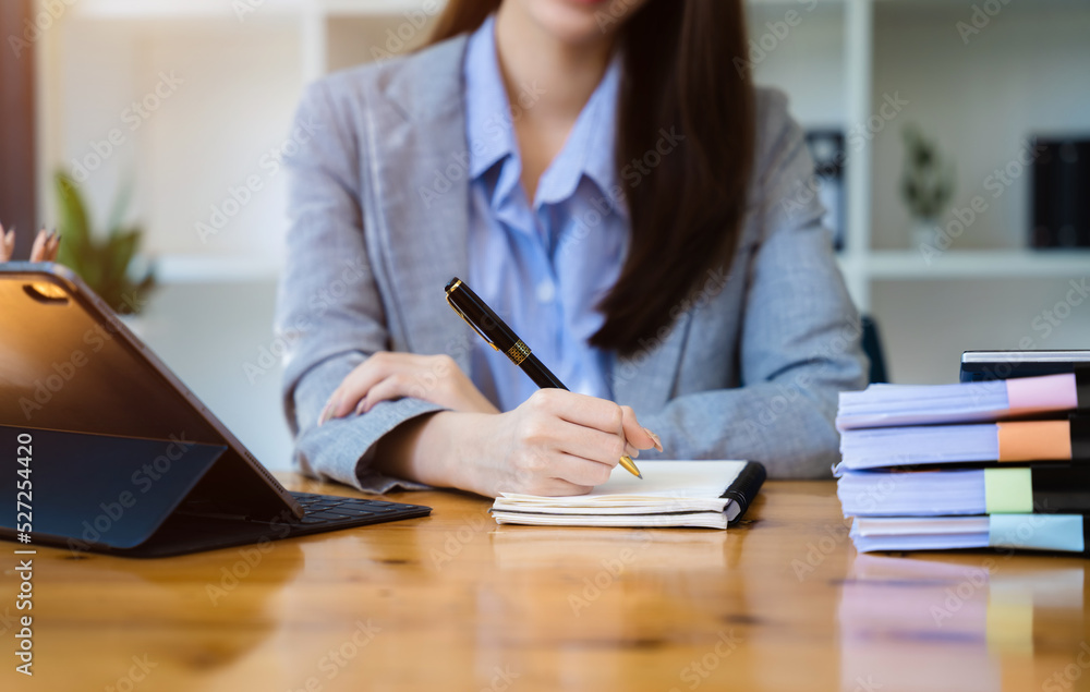 Business women writing on a notepad with a pen in the office. Business women writing on a notepad with a pen in the office.
