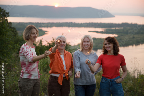 multi generation a group of women friends with sparklers has fun spending time together in nature on a summer evening