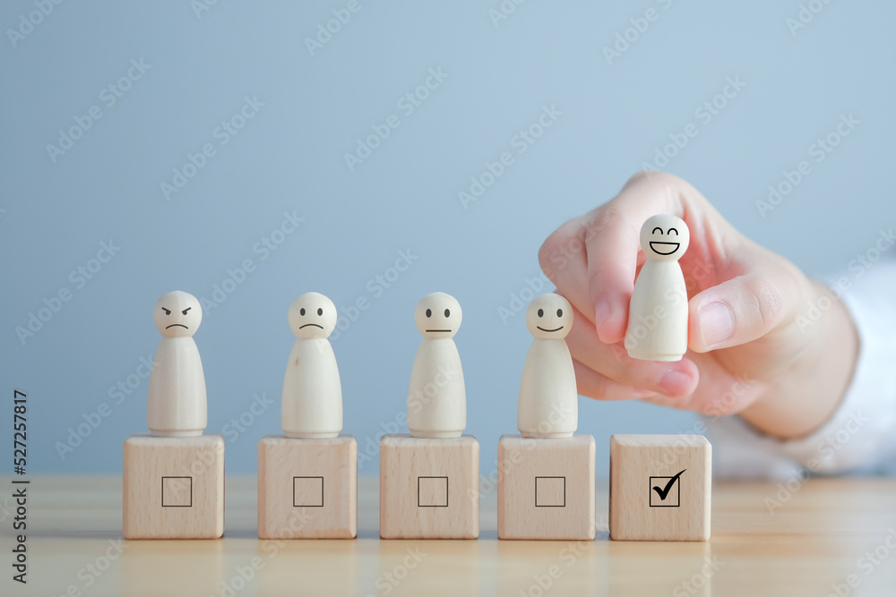 Hand pick happy face wooden figure. Customer service rating experience and feedback emotion and satisfaction survey. Human Resources management choosing positive attitude to team leader.