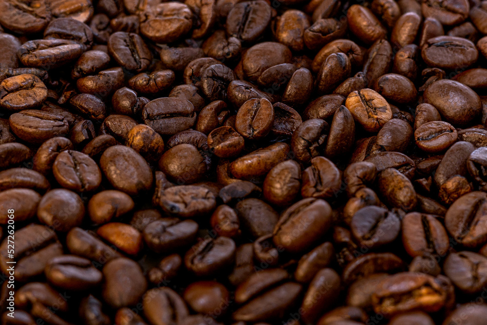 Naklejka premium Coffee beans background. Grão de café. Fullframe shot of fresh roastend coffee beans zoom in. Aromatic brown textured seeds on background from close up. Black energy structured grain on backdrop. 