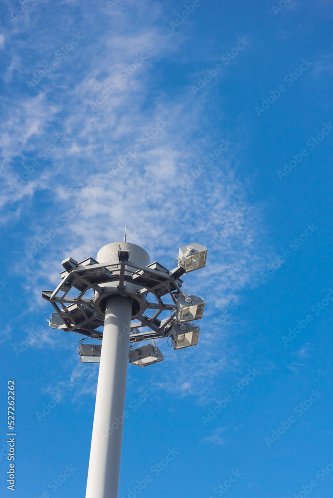 Lookup close up view of high mast lighting pole lights tower with antenna under cloud blue sky in Japan