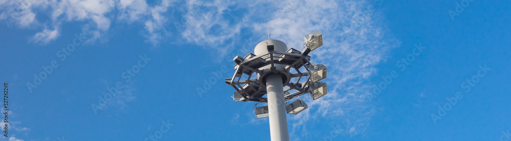 Panorama close up view of high mast lighting pole lights tower with antenna under cloud blue sky in Japan