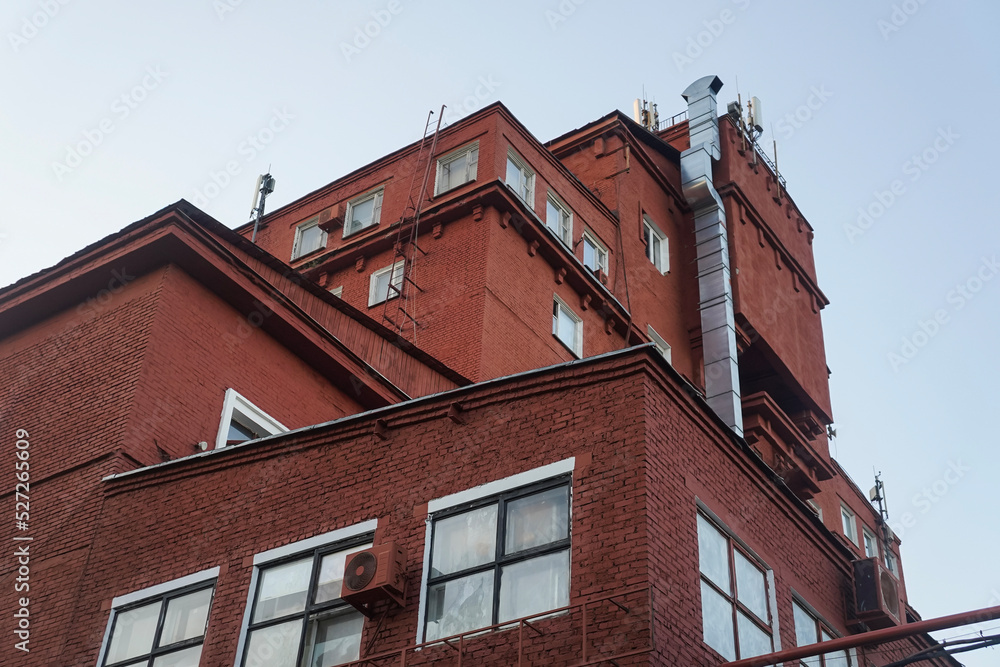 Red brick building with square windows and metal duct