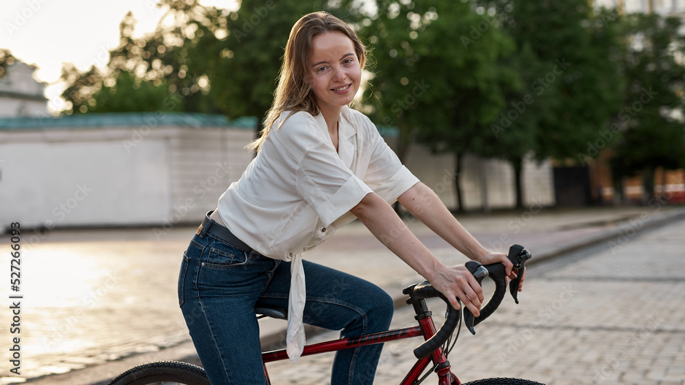 Obraz premium Side view of girl with her bicycle on city square