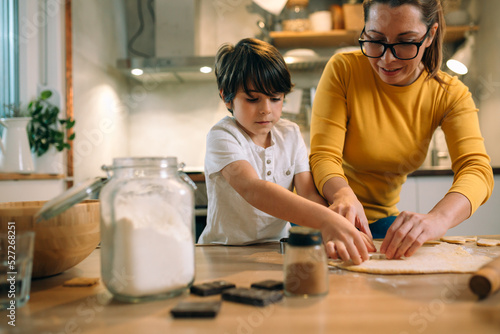 mother and son making cookies with cookie cutter in kitchen