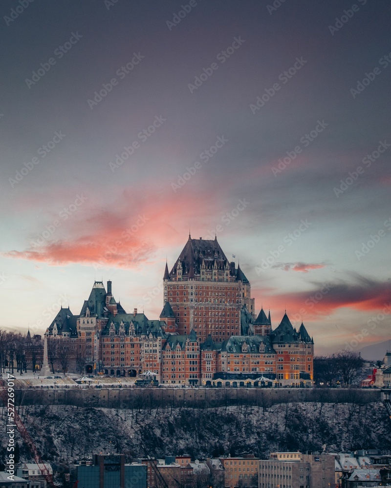Fototapeta premium Vertical breathtaking view of old castle on pink sunset sky background in Quebec City
