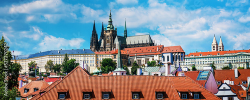 Panoramic photo of old Prague castle and church under blue sky. Chech Republic historical architecture.