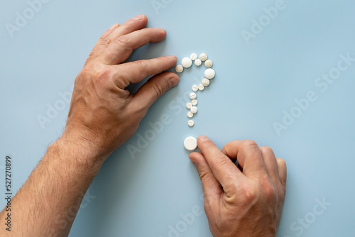 Hands folding pills in the form of a question mark. Concept of drug addiction temptation or preparation for the cold season. 