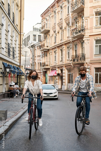 Young couple wearing medical masks riding bikes © Svitlana