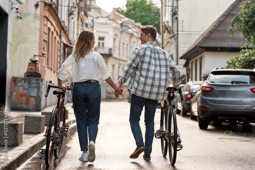 Couple walk with bicycles and look at each other