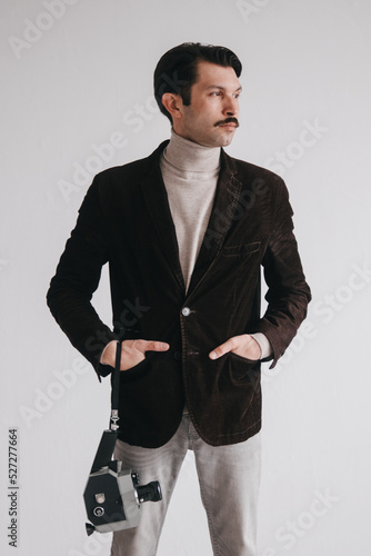 a young man in jeans and a jacket poses against a white wall in the studio.
